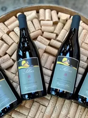 4 bottles laying on top of wine corks on a half barrel